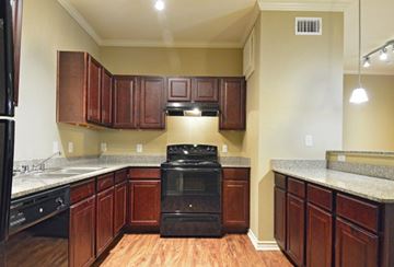 Orange apartment for rent - A kitchen with wooden cabinets and a black stove top oven.