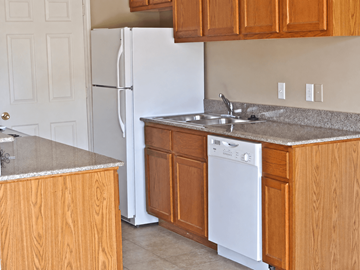Silsbee apartment for rent - A white refrigerator stands in a kitchen with wooden cabinets.