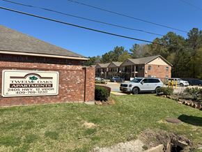 Vidor apartment for rent - A sign for Twelve Oaks Apartments is in front of a brick building.