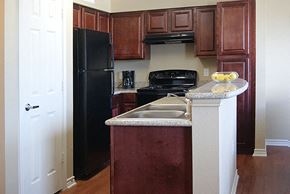 Fort Worth apartment for rent - A kitchen with a black refrigerator and brown cabinets.