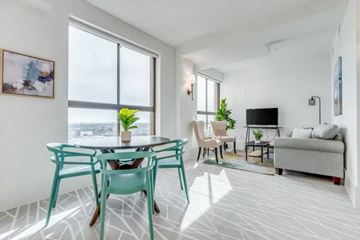 Galveston apartment for rent - A living room with a white couch, a black TV, and a dining table with chairs.