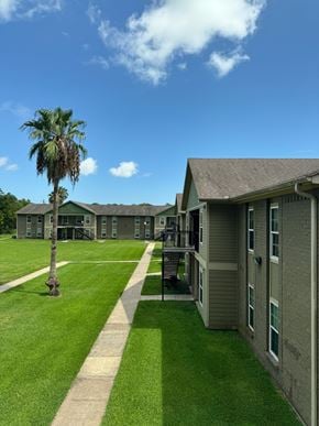 Freeport apartment for rent - A building with a green lawn and a palm tree in front.