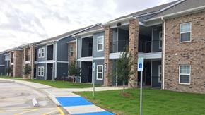 Orange apartment for rent - Apartment building with a blue painted area in front.