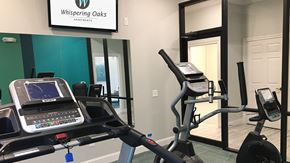 Orange apartment for rent - A Whispering Oaks Apartments gym with a treadmill and elliptical trainer.