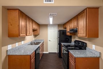 Port Arthur apartment for rent - A kitchen with wooden cabinets and black appliances.