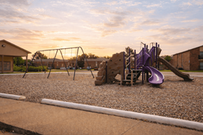 Port Arthur apartment for rent - A playground with a purple slide and a brown building in the background.