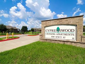 Orange apartment for rent - a sign for cypresswood crossing apartments in front of a building