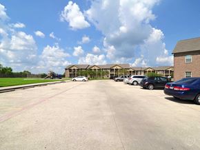 Orange apartment for rent - a parking lot with cars in front of apartment buildings