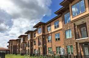 Tomball apartment for rent - A row of brown brick apartment buildings with green shutters and balconies.