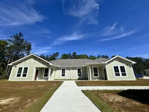 Lumberton apartment for rent - A house with a grey roof and white walls is surrounded by a grassy area.