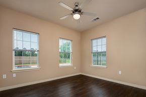 Beaumont apartment for rent - an empty living room with a ceiling fan and three windows