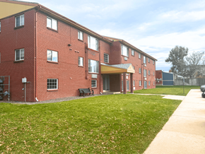 Denver apartment for rent - A red brick building with a green lawn in front at Townview Plaza Apartments, Denver, CO, 80204.