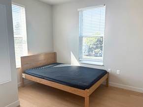 Denver apartment for rent - A bed with a black mattress is in a room with a window.