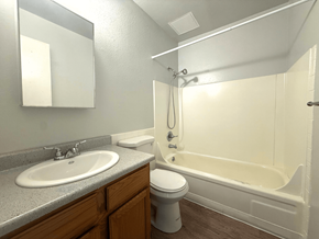 Westminster apartment for rent - A bathroom with a white tub, sink, and toilet at Mountain Terrace Apartments, Westminster, Colorado.