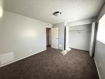 A room with carpeted floor and a doorway leading to another room.