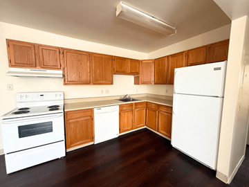 Denver apartment for rent - A kitchen with white appliances and wooden cabinets.