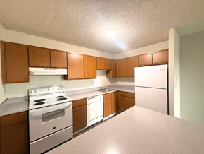 Arvada apartment for rent - A kitchen with white appliances and wooden cabinets.