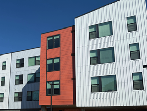 Denver apartment for rent - A red building stands out next to white buildings with black windows.