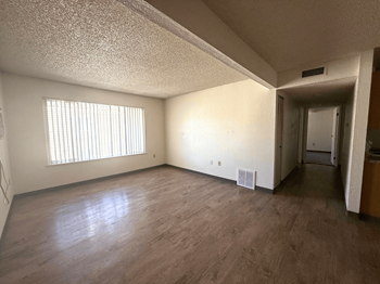 A room with wooden flooring and a window with blinds.