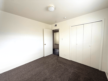 A room with a carpeted floor and a white ceiling with a smoke detector.