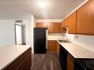Arvada apartment for rent - A kitchen with wooden cabinets and a black fridge.