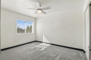 Fort Morgan apartment for rent - A room with a ceiling fan and a window showing a view of trees at Gateway Village Apartments in Fort Morgan, CO, 80701