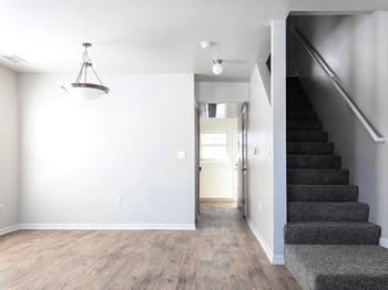 A room with a staircase and a light hanging from the ceiling.