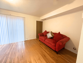 Lakewood townhouse for rent - A red couch with two pillows sits in a room with wooden floors and a sliding glass door.