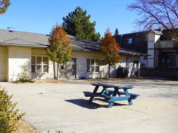 A blue picnic table is in front of a yellow building.
