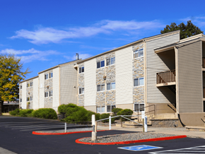 Denver apartment for rent - A parking lot in front of a building with a blue handicap parking sign at Garden Court Apartments, Denver, CO, 80220