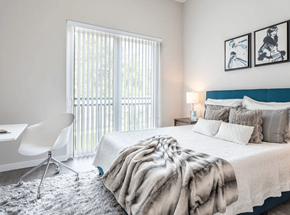 Norwalk apartment for rent - A bedroom with a large bed, a chair, and a window with blinds.