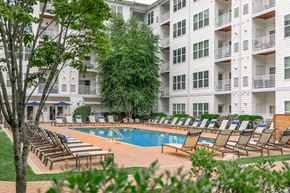 Norwalk apartment for rent - A pool area with sun loungers and a white building in the background.