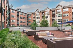 Norwalk apartment for rent - A patio area with couches and tables in front of apartment buildings.