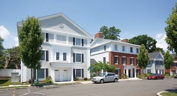 Stamford apartment for rent - A white two story house with a red car parked in front.