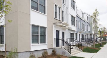 Stamford apartment for rent - A row of townhouses with white and grey exteriors and black railings.