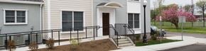 Stamford apartment for rent - A grey house with a black railing and a brown door.