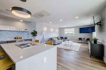 Pflugerville apartment for rent - A modern kitchen with a large island and a living room with a couch and a TV.