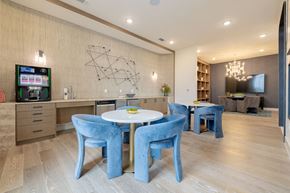 Austin apartment for rent - a dining room with blue chairs and a white table and a television