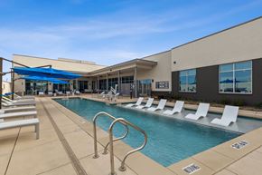 North Richland Hills apartment for rent - Resort-style swimming pool with lounge chairs and apartment building in the background