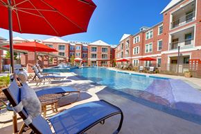 Frisco apartment for rent - A pool surrounded by red umbrellas and chairs.