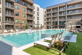 Austin apartment for rent - A swimming pool surrounded by lounge chairs and apartment buildings.