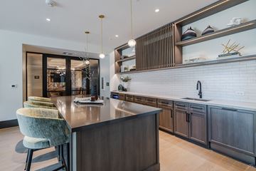 Austin apartment for rent - A modern kitchen with a dark wood island and green chairs.