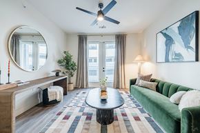 Austin apartment for rent - A living room with a green couch and a round mirror on the wall.