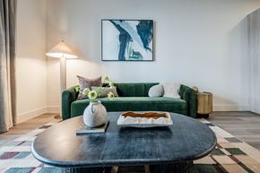 Austin apartment for rent - A living room with a green couch, a round table with a plate of food, and a painting on the wall.