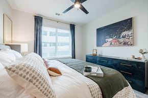 Austin apartment for rent - A bedroom with a large bed, a ceiling fan, and a painting on the wall.