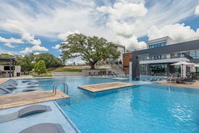 Austin apartment for rent - A large outdoor swimming pool with a wooden deck and lounge chairs.
