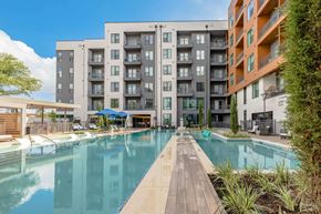 Austin apartment for rent - A large swimming pool in front of a modern apartment building.