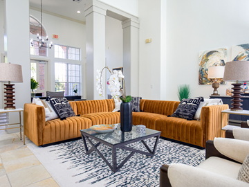 Houston apartment for rent - A living room with a large orange couch and a glass coffee table.