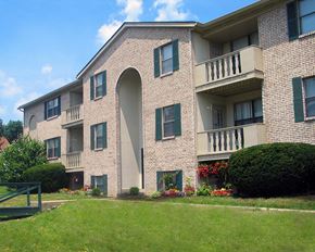 Cincinnati apartment for rent - a large brick apartment building with a green lawn and bushes  at Four Worlds Apartments, Cincinnati