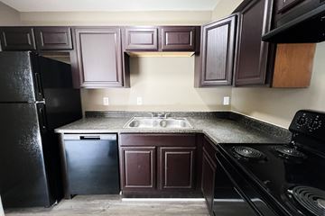 Hamilton apartment for rent - A kitchen with dark brown cabinets and black appliances.